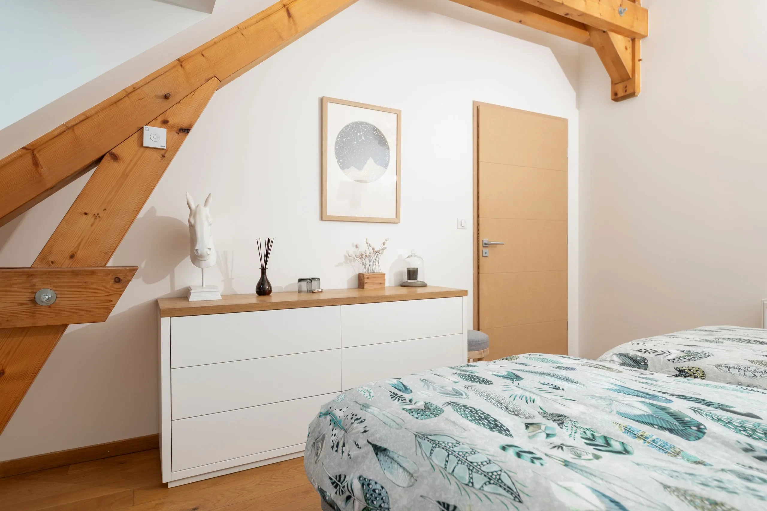 Chambre lumineuse avec poutres en bois apparentes.