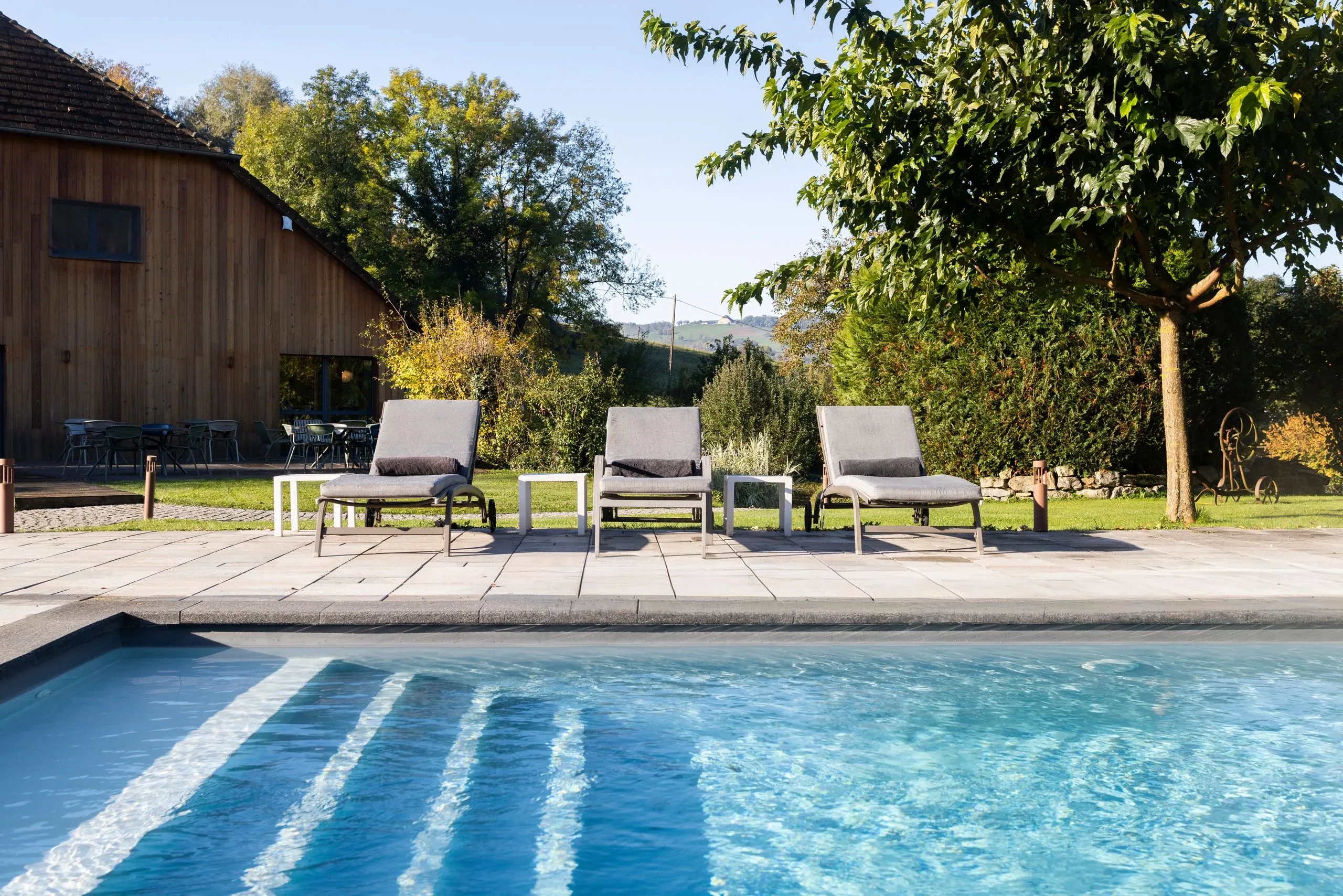 Piscine extérieure avec transats et jardin verdoyant - Spa Jura - Domaine La Scierie