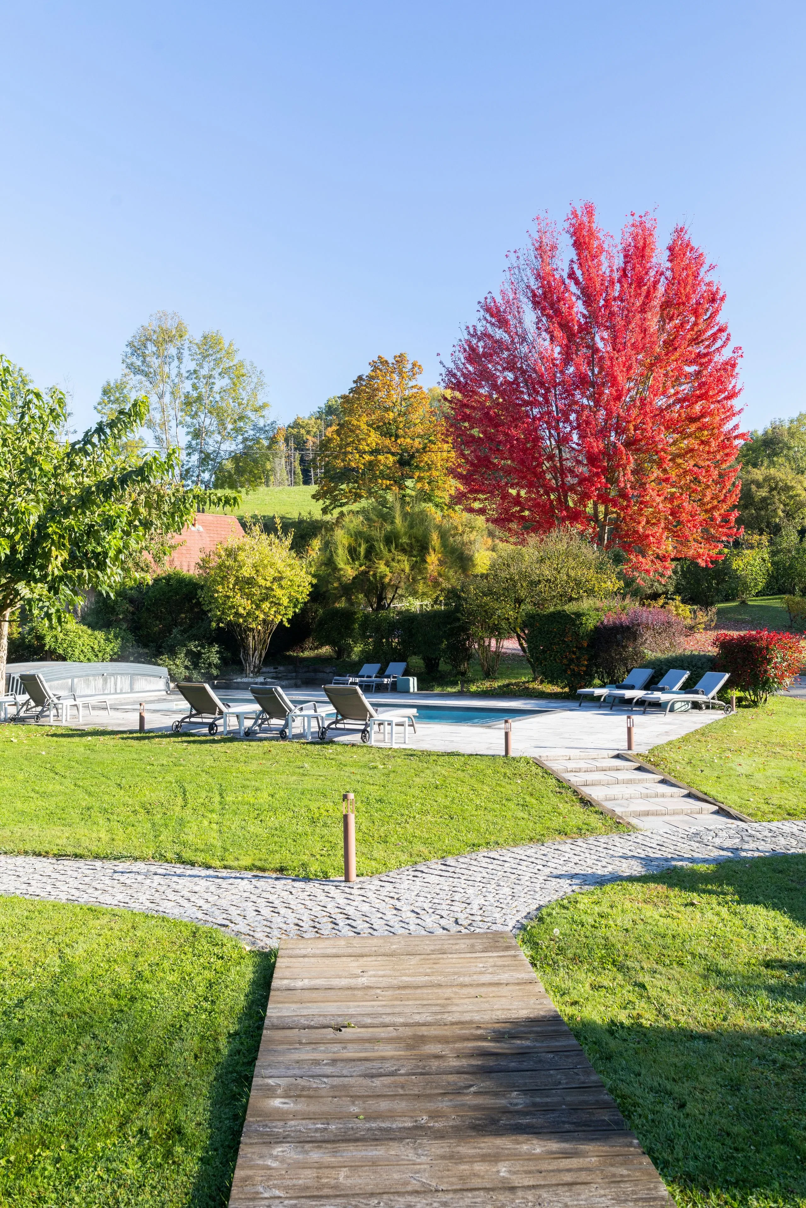 Piscine extérieure entourée d’arbres colorés en automne - Chambre d'hôtes Jura - Domaine La Scierie
