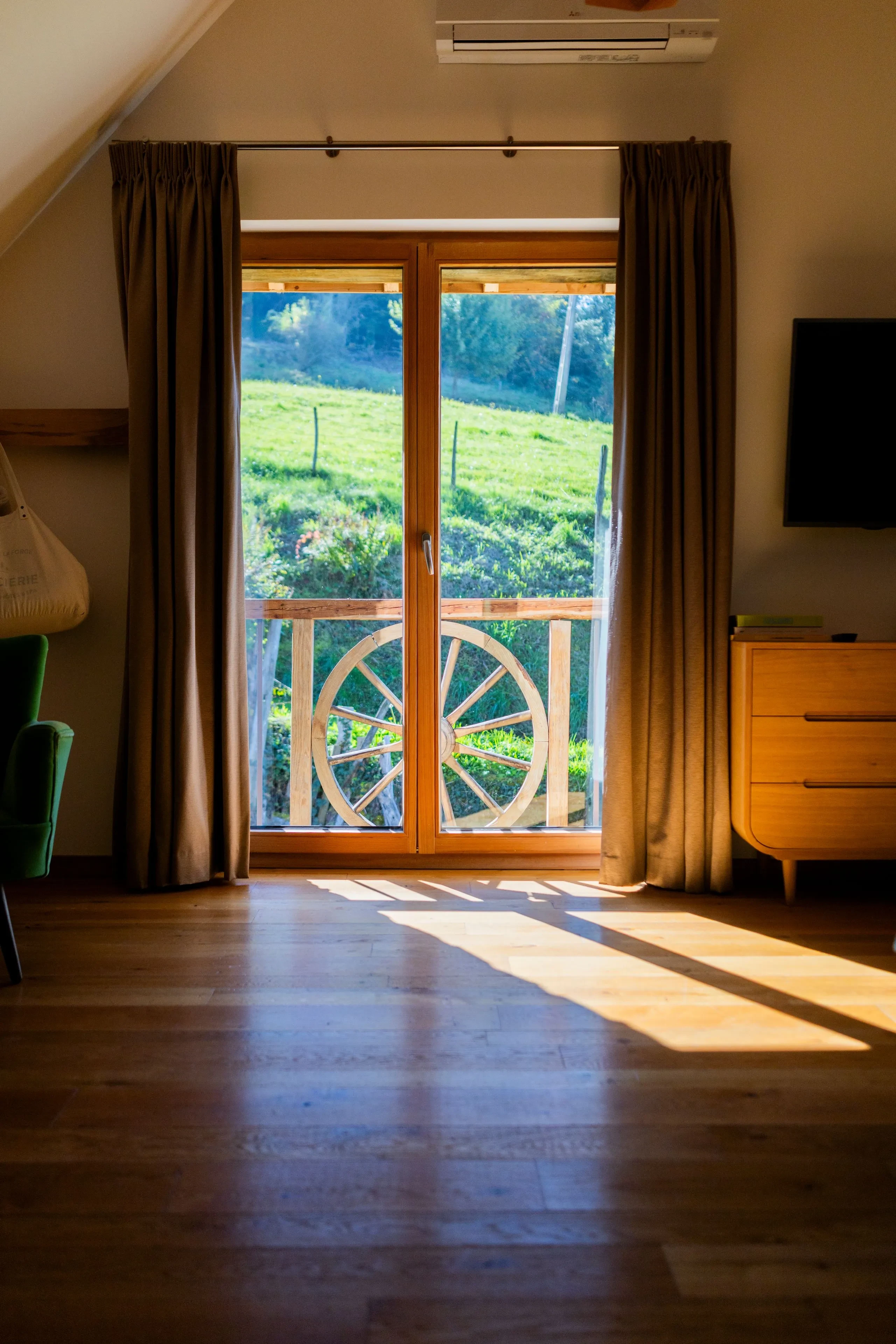 Porte-fenêtre en bois donnant sur un champ vert