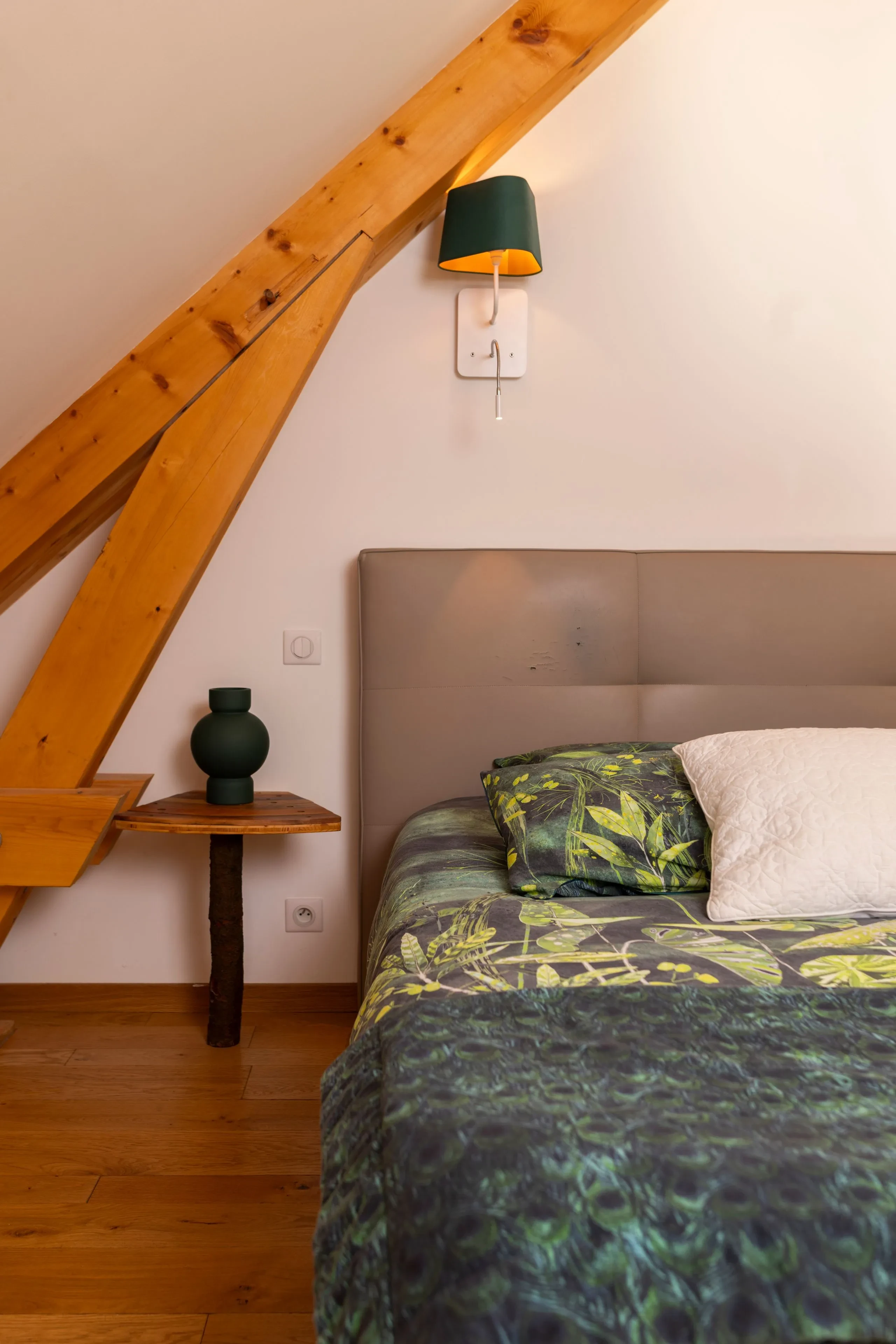 Chambre mansardée avec lit et lampe murale