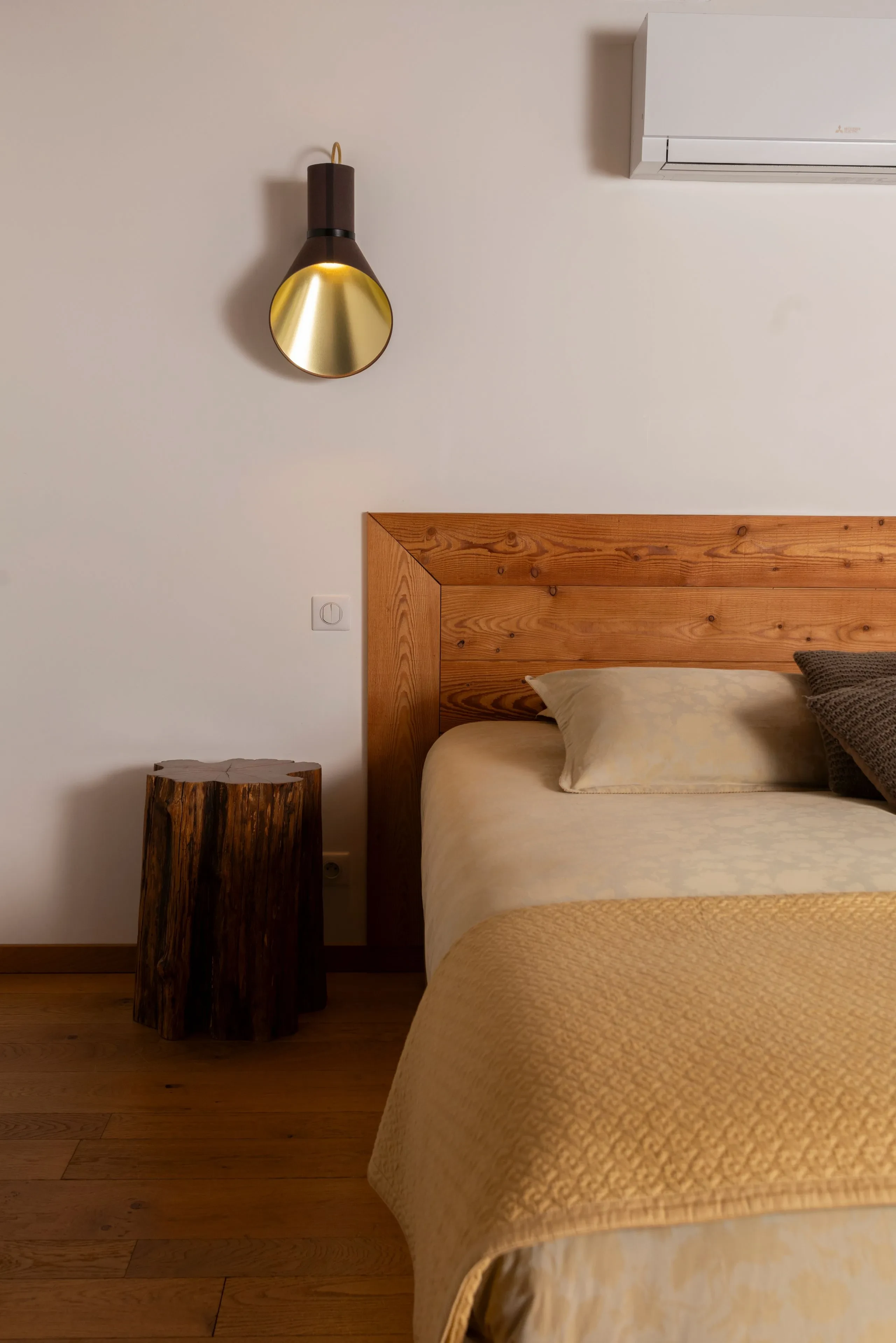 Chambre avec lit en bois et lampe murale dorée