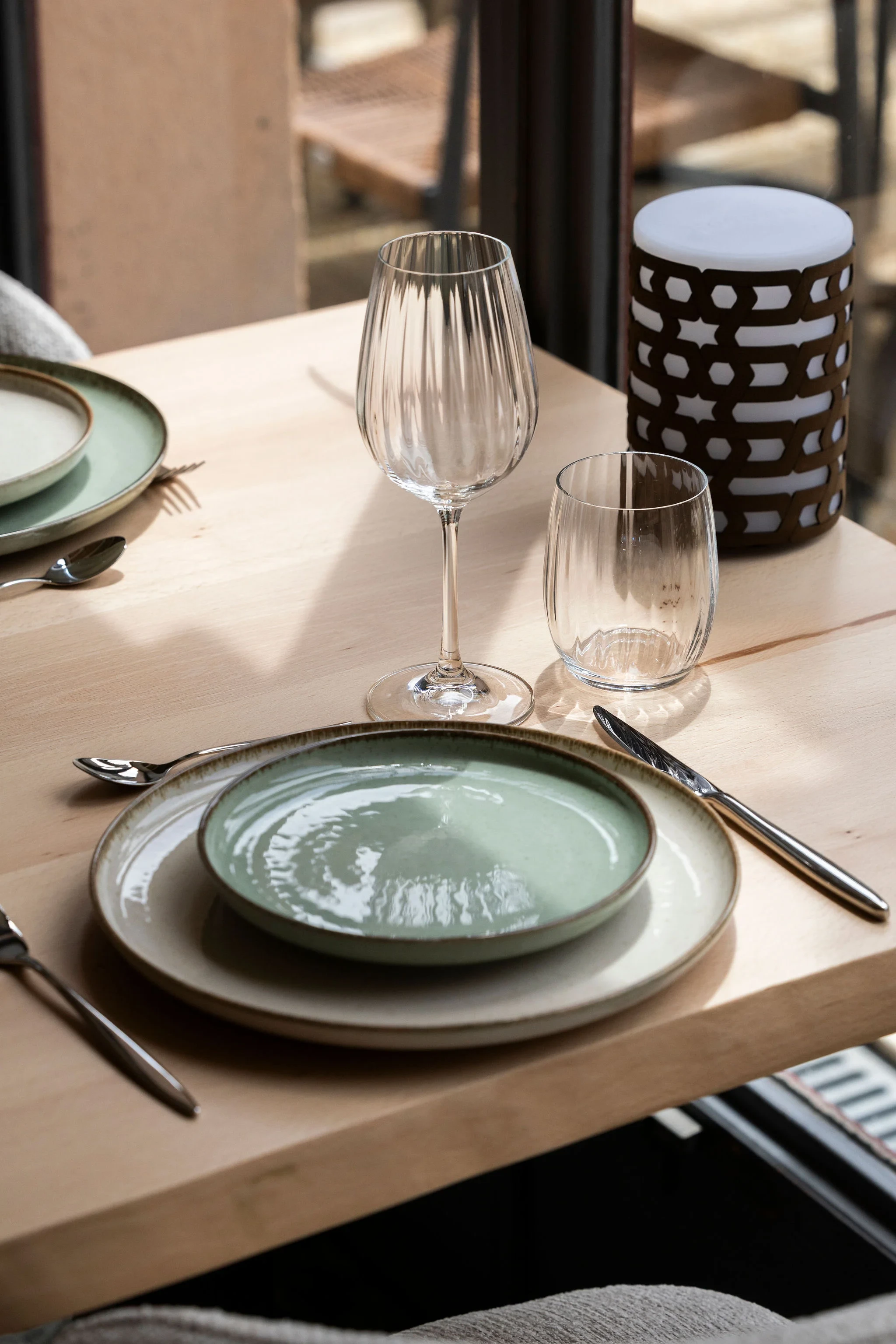 Table dressée avec assiettes vertes et verres