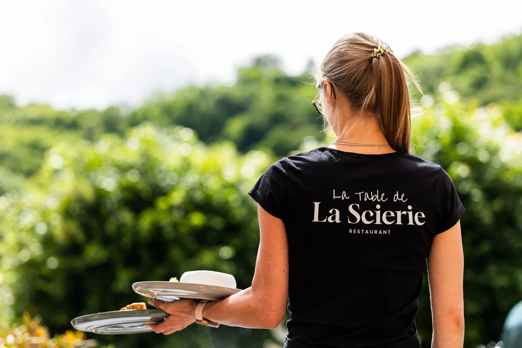 Serveuse restaurant devant vignoble verdoyant